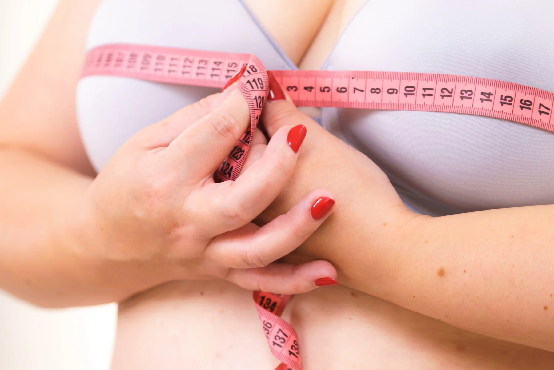 Woman measuring her breasts with a tape measurer.